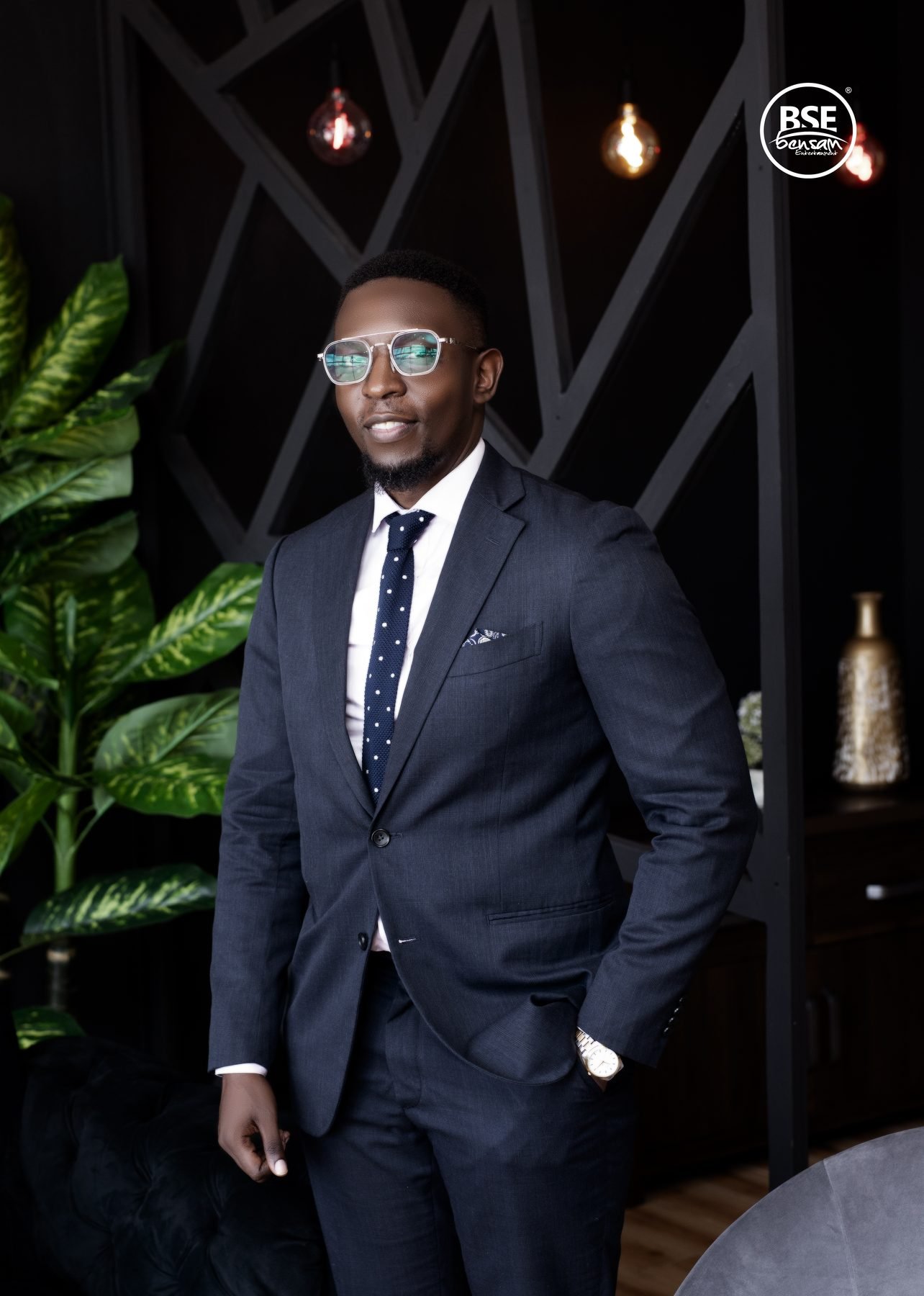 Executive in a navy suit beside a monstera plant