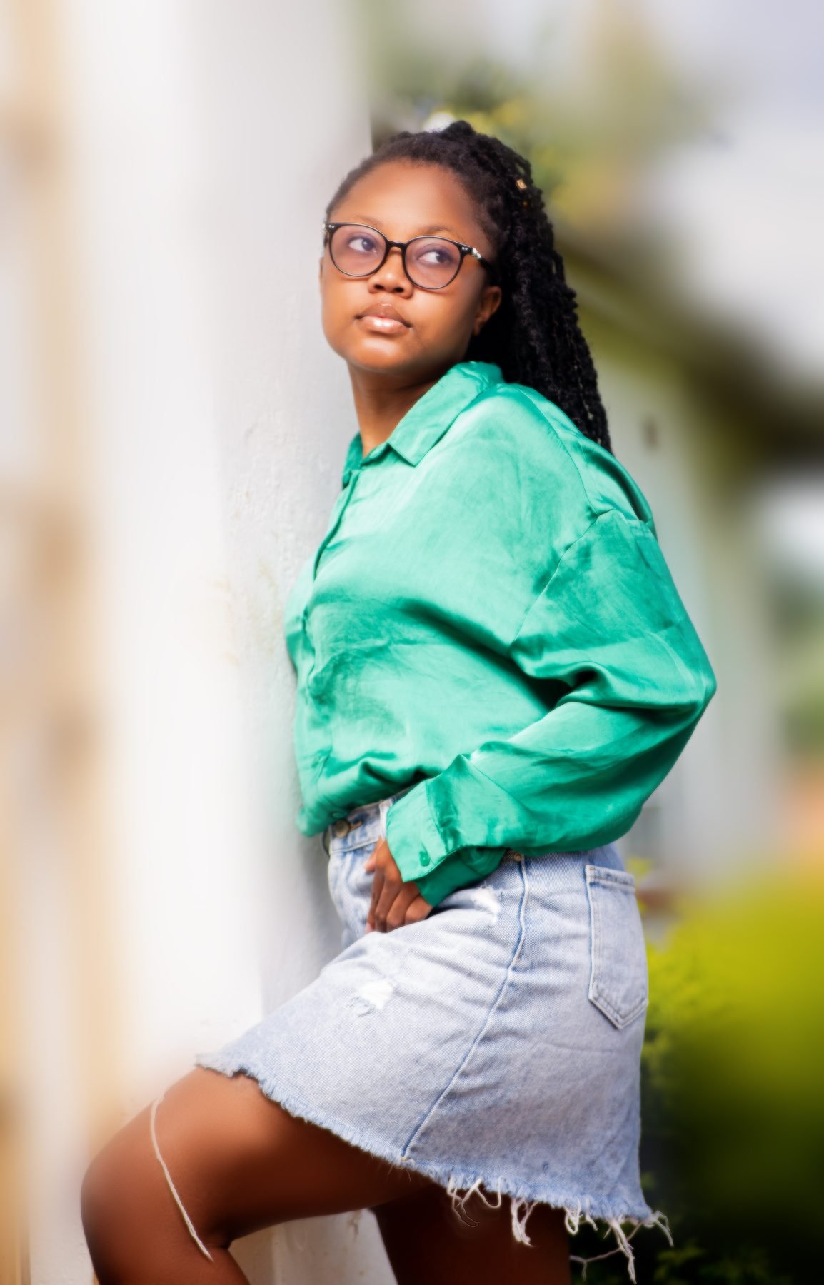 Woman in a green shirt leaning against a wall